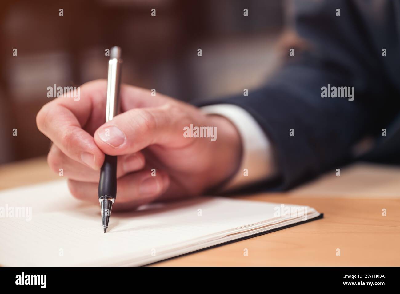 Primo piano della mano maschile con un uomo d'affari che scrive appunti e commenti su un taccuino, attenzione selettiva Foto Stock