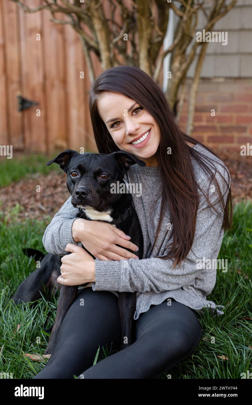 Una donna contenta abbraccia il suo fedele cane in un ambiente accogliente Foto Stock