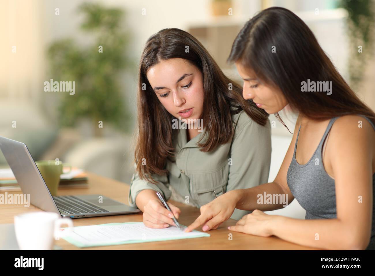 Telelavoratore che spiega dove firmare il contratto con il suo collega a casa Foto Stock