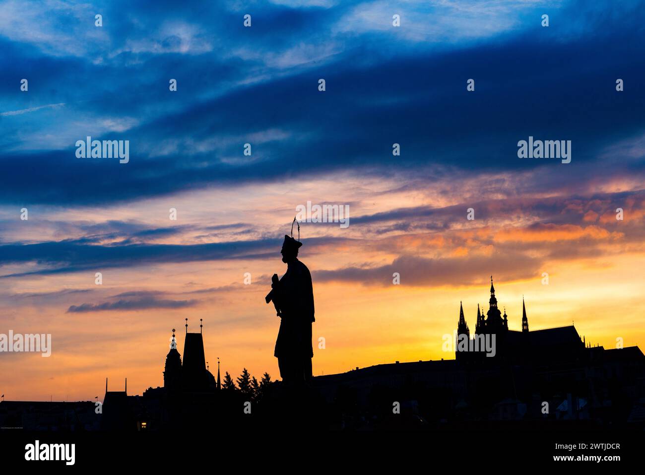 St Statua di Giovanni di Nepomuk sul Ponte Carlo; Praga; Repubblica Ceca; con la catadrale di San Vito e la Torre del Ponte del piccolo quartiere; tramonto Foto Stock
