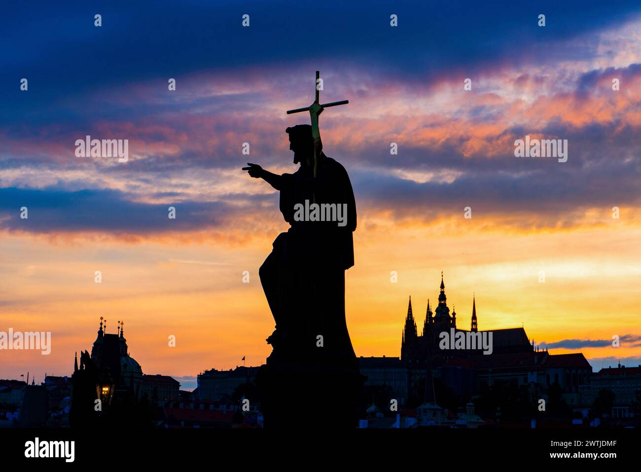 Statua di San Giovanni Battista sul Ponte Carlo, Praga, Repubblica Ceca, con la cattedrale di San Vito e la Torre del Ponte del piccolo quartiere Foto Stock
