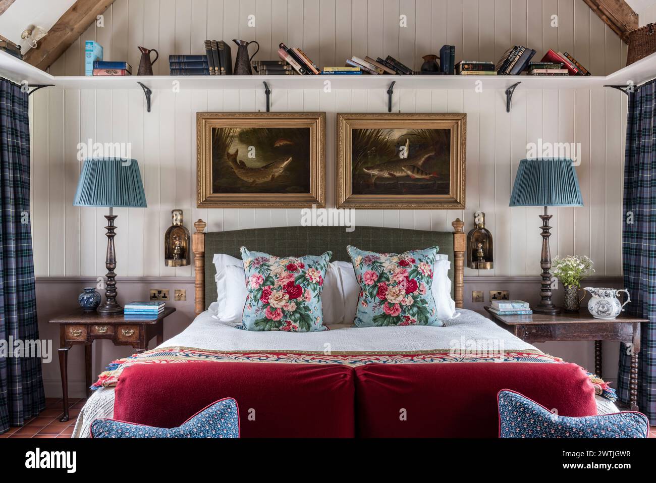 Scaffale di libri sopra il letto con cuscini e lampade floreali in un hotel di lusso ad Ardfin sull'isola di Giura, Ebridi interne, Scozia, Regno Unito Foto Stock