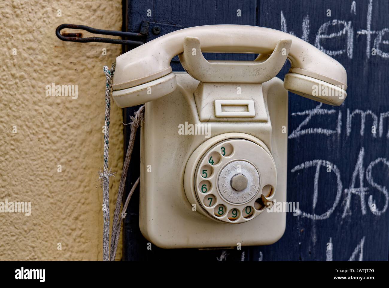 Ein uraltes weißes Telefon mit Wählscheibe an der Wand Foto Stock