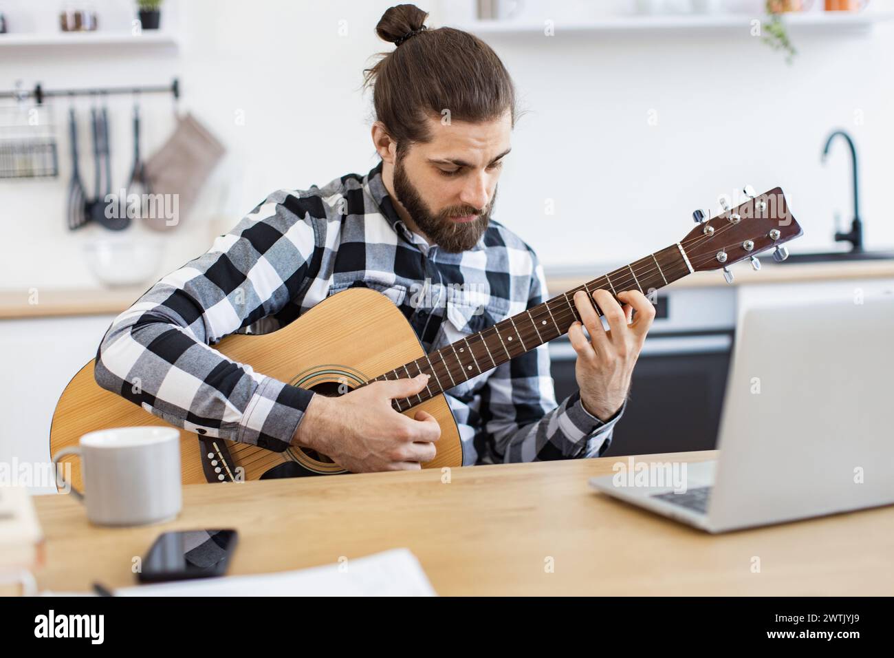Un adulto barbuto che posa con la chitarra mentre si gode un piacevole passatempo a casa. Foto Stock