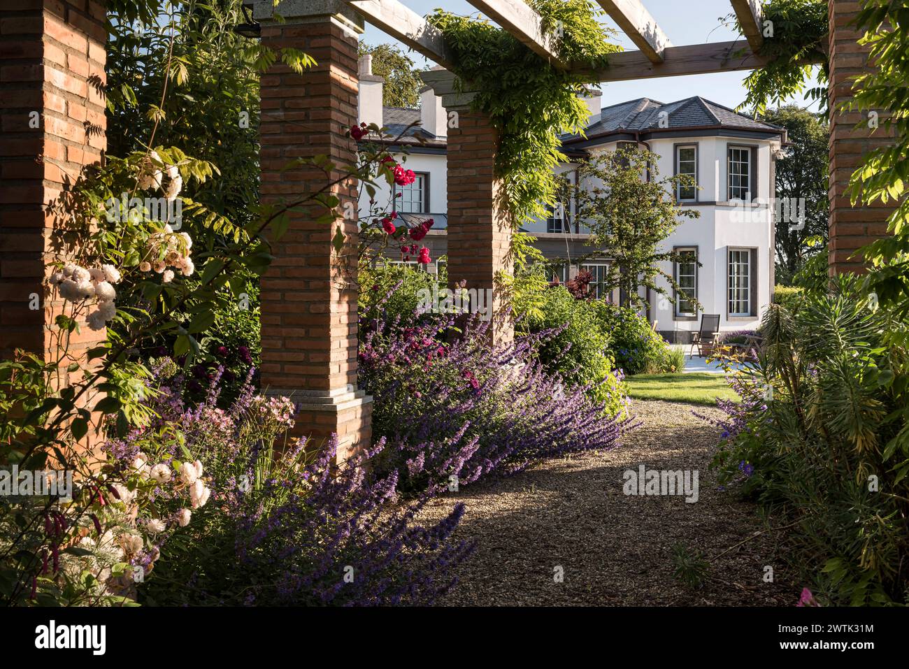 Sentiero di ghiaia con piante in fiore e pergola nei giardini della casa di campagna di Greystones, contea di Wicklow, Irlanda Foto Stock