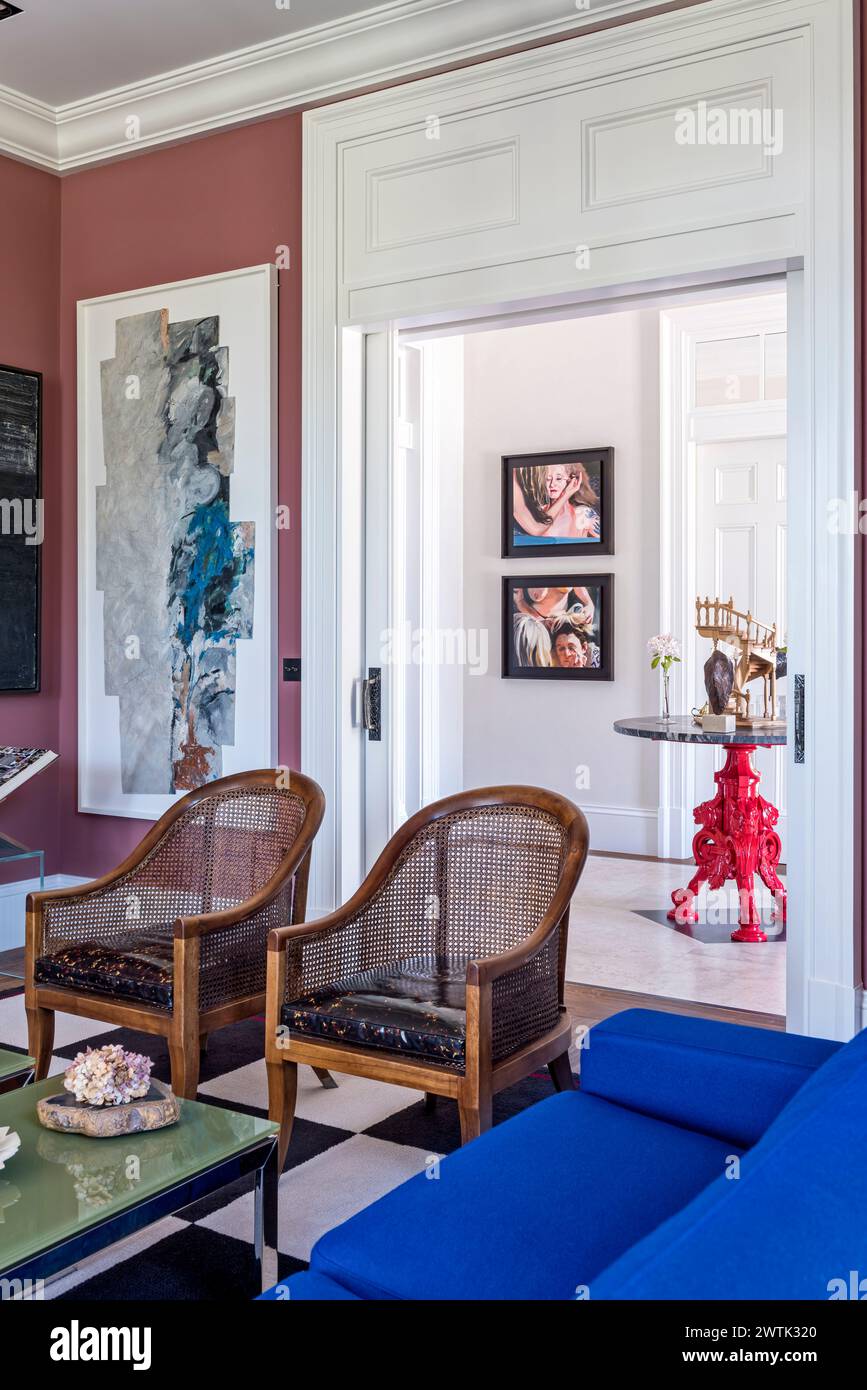 Coppia di poltrone in vimini con vista attraverso la porta scorrevole verso il tavolo cinese a tre zampe nella casa irlandese di Greystones, contea di Wicklow, Irlanda Foto Stock