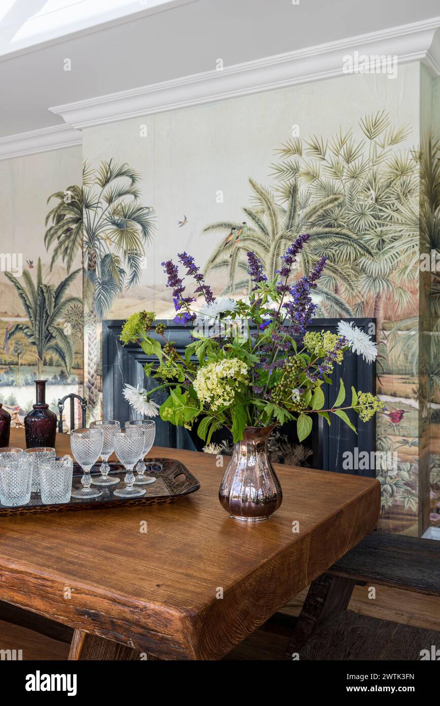 Eleganti fiori tagliati su un tavolo in legno con decorazioni a parete di palme tropicali nella casa irlandese di Greystones, nella contea di Wicklow, Irlanda Foto Stock