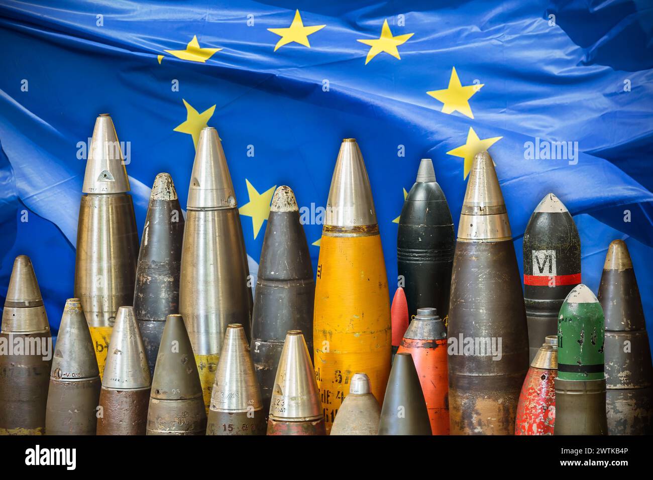 Bombe e munizioni militari di fronte a una bandiera dell'Unione europea che ondeggia Foto Stock