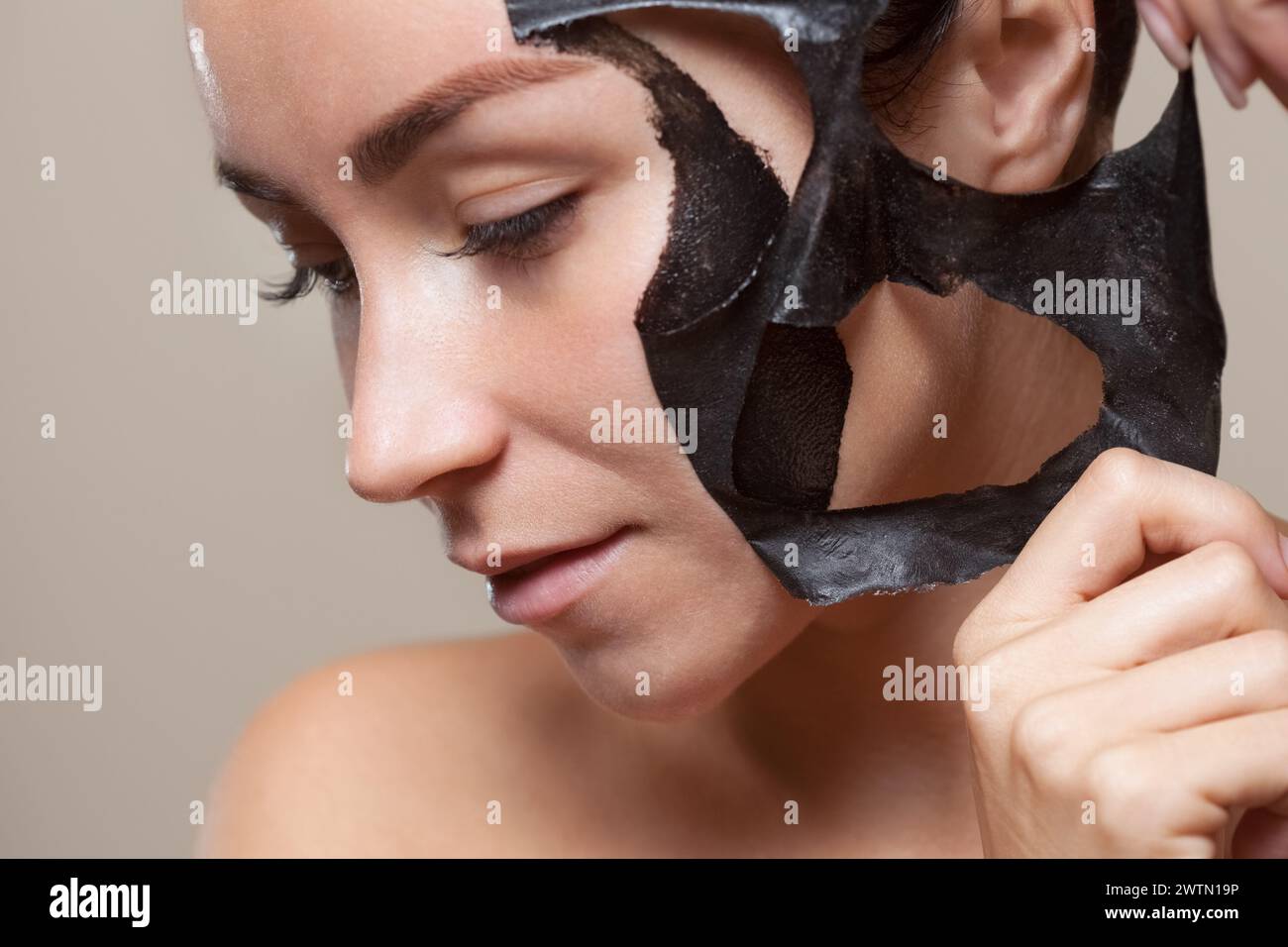 una maschera nera al volto di una bella donna. Trattamenti spa e cura dei gatti nel salone di bellezza. Foto Stock