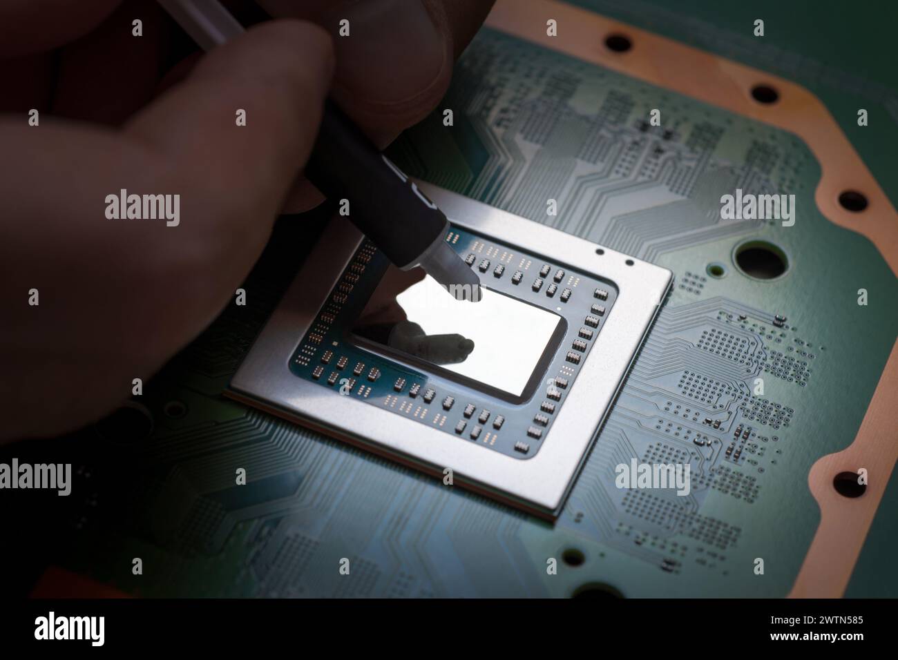 Un tecnico comprime la pasta termica fresca sulla CPU. Unità di elaborazione centrale Foto Stock