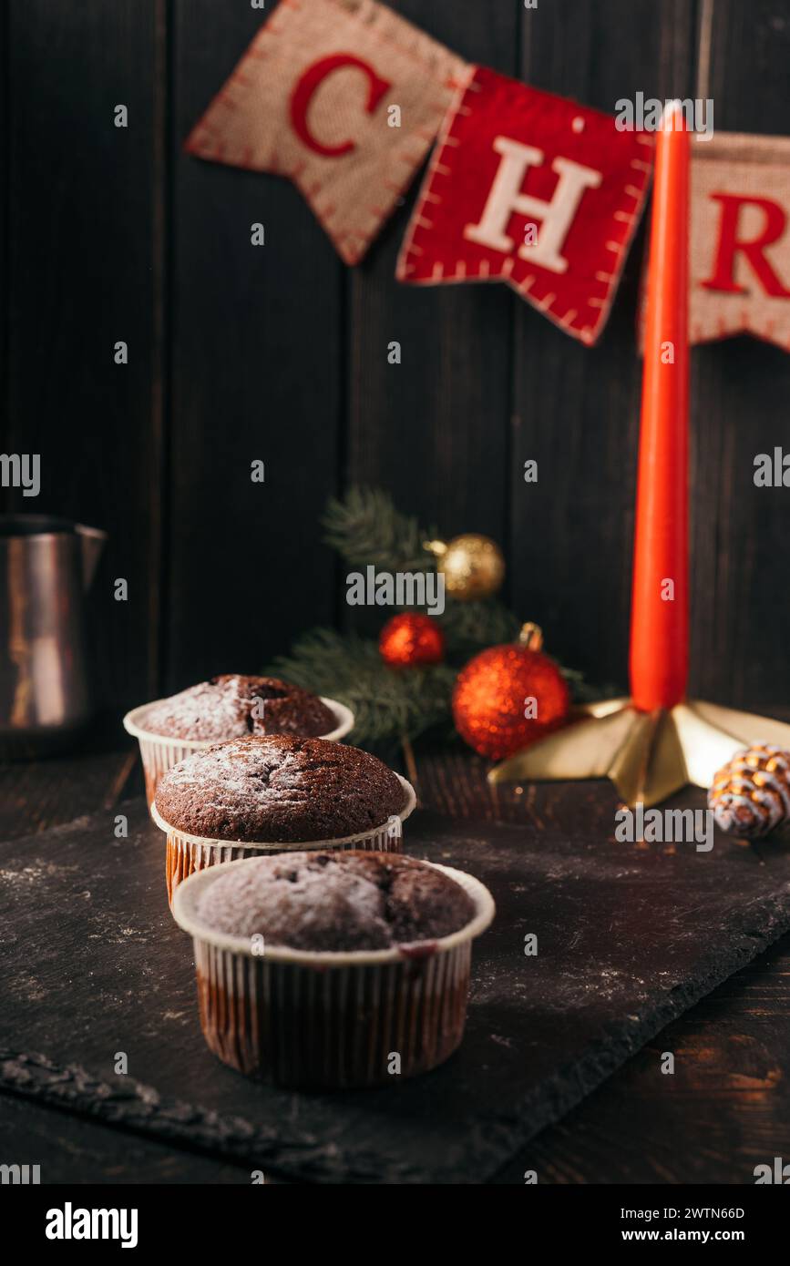muffin al cioccolato con zucchero a velo su sfondo nero. Decorazione natalizia . Ancora vita da vicino. Foto del cibo. Foto Stock