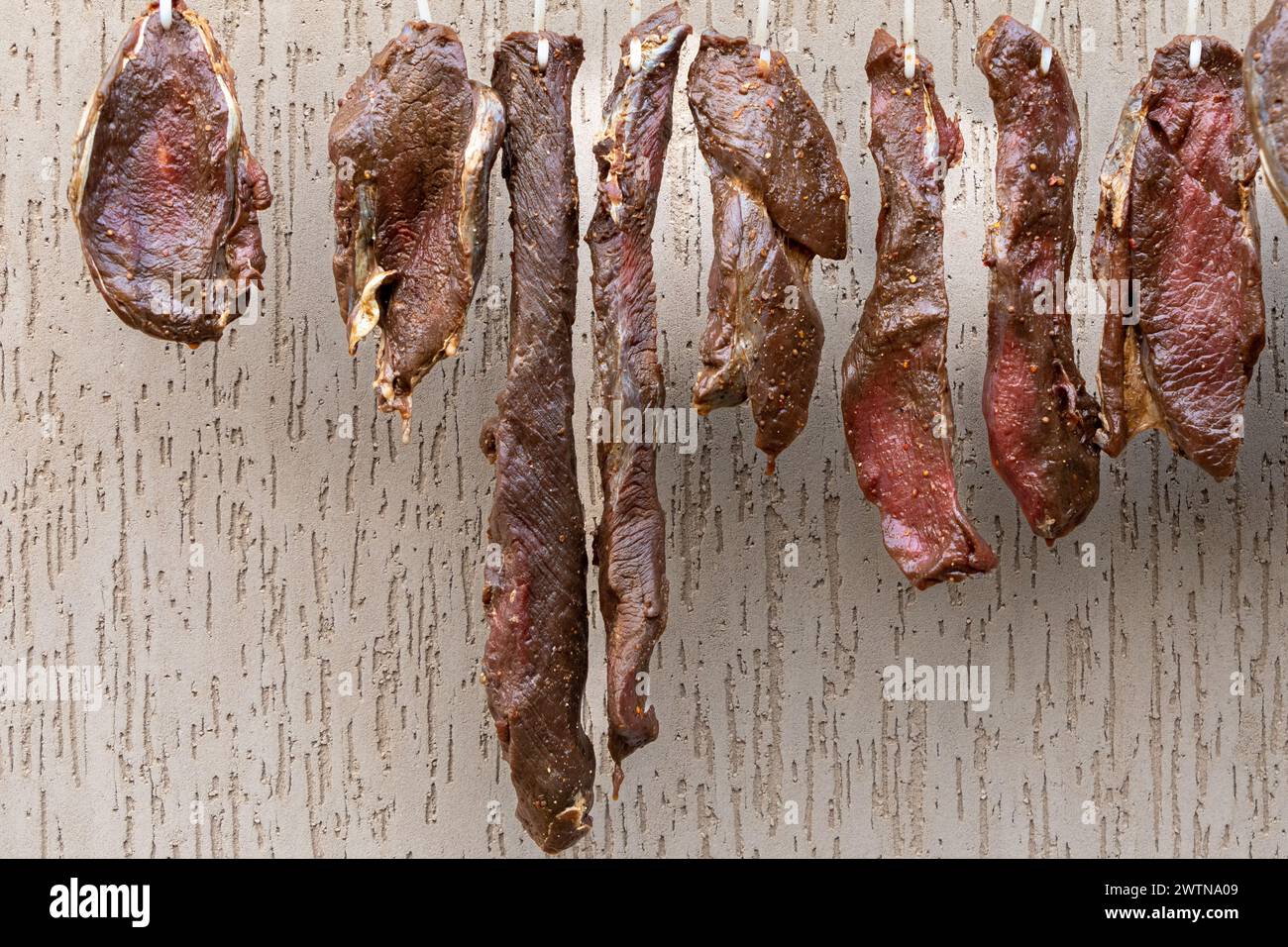 Pezzi di manzo speziato crudo appesi all'esterno per diventare un popolare piatto sudafricano chiamato biltong. Il biltong è un prodotto a base di carne salata. Foto Stock