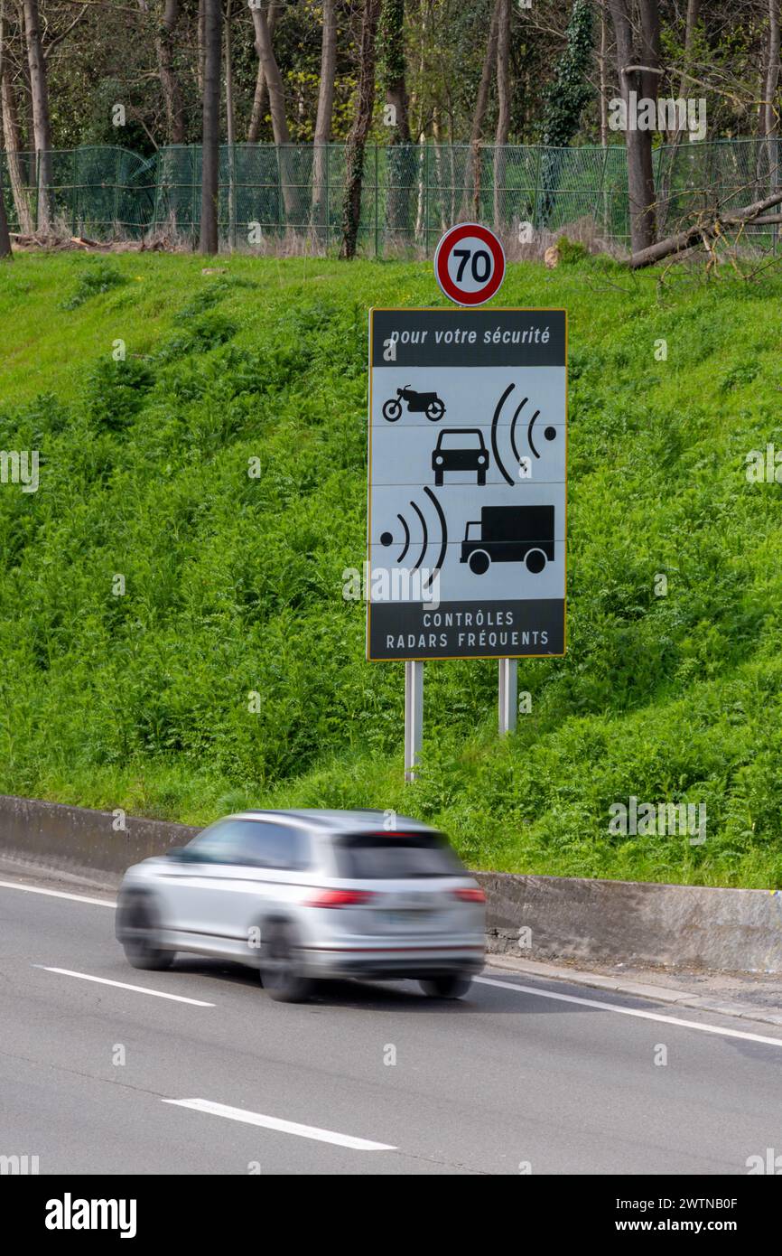 Auto con sfocatura del movimento che si muove oltre un cartello stradale che indica frequenti controlli della velocità radar sul lato di una strada francese Foto Stock