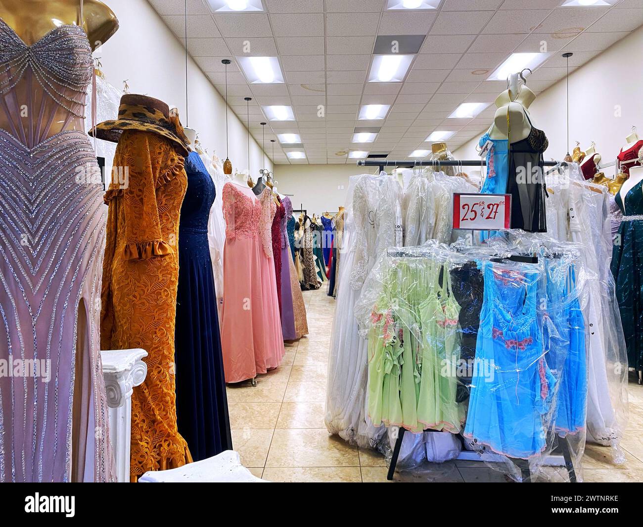 Interno di un negozio di abbigliamento, con abiti multicolore appesi su scaffali, concetto di vendita al dettaglio di abbigliamento Foto Stock