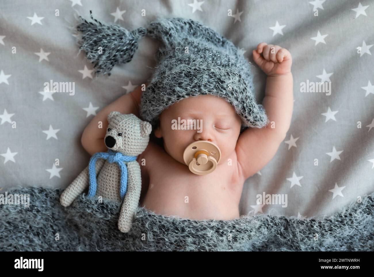 Bambino neonato carino in cappello caldo con giocattolo che dorme sul letto, vista dall'alto Foto Stock