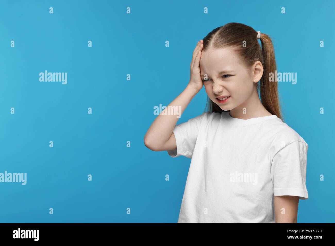 Bambina che soffre di mal di testa su sfondo azzurro. Spazio per il testo Foto Stock