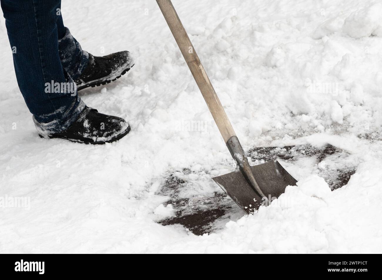 Un lavoratore esperto pulisce efficacemente la neve utilizzando una pala in ferro con un robusto manico in legno. Un operatore professionista esperto rimuove rapidamente la neve Foto Stock