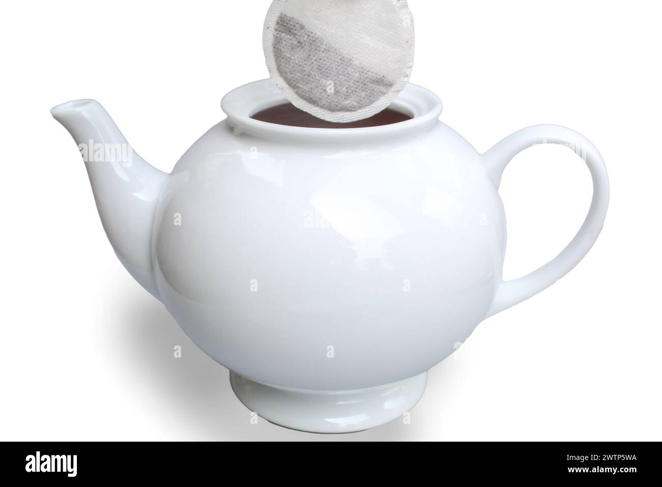 Aggiunta di una bustina da tè alla teiera su sfondo bianco Foto Stock
