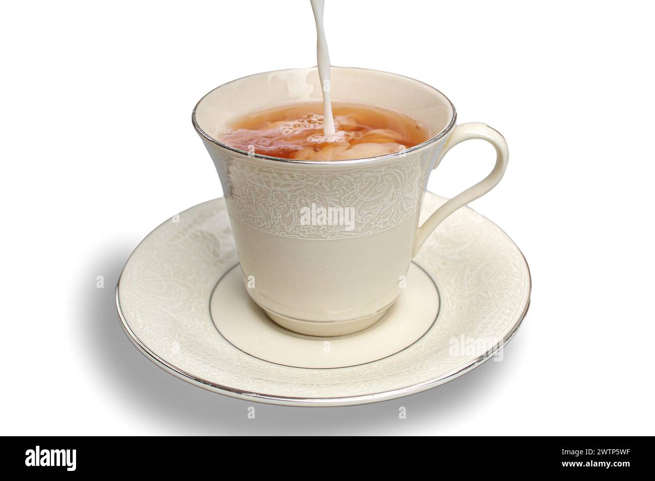 Il latte viene versato in una tazza di tè su sfondo bianco Foto Stock