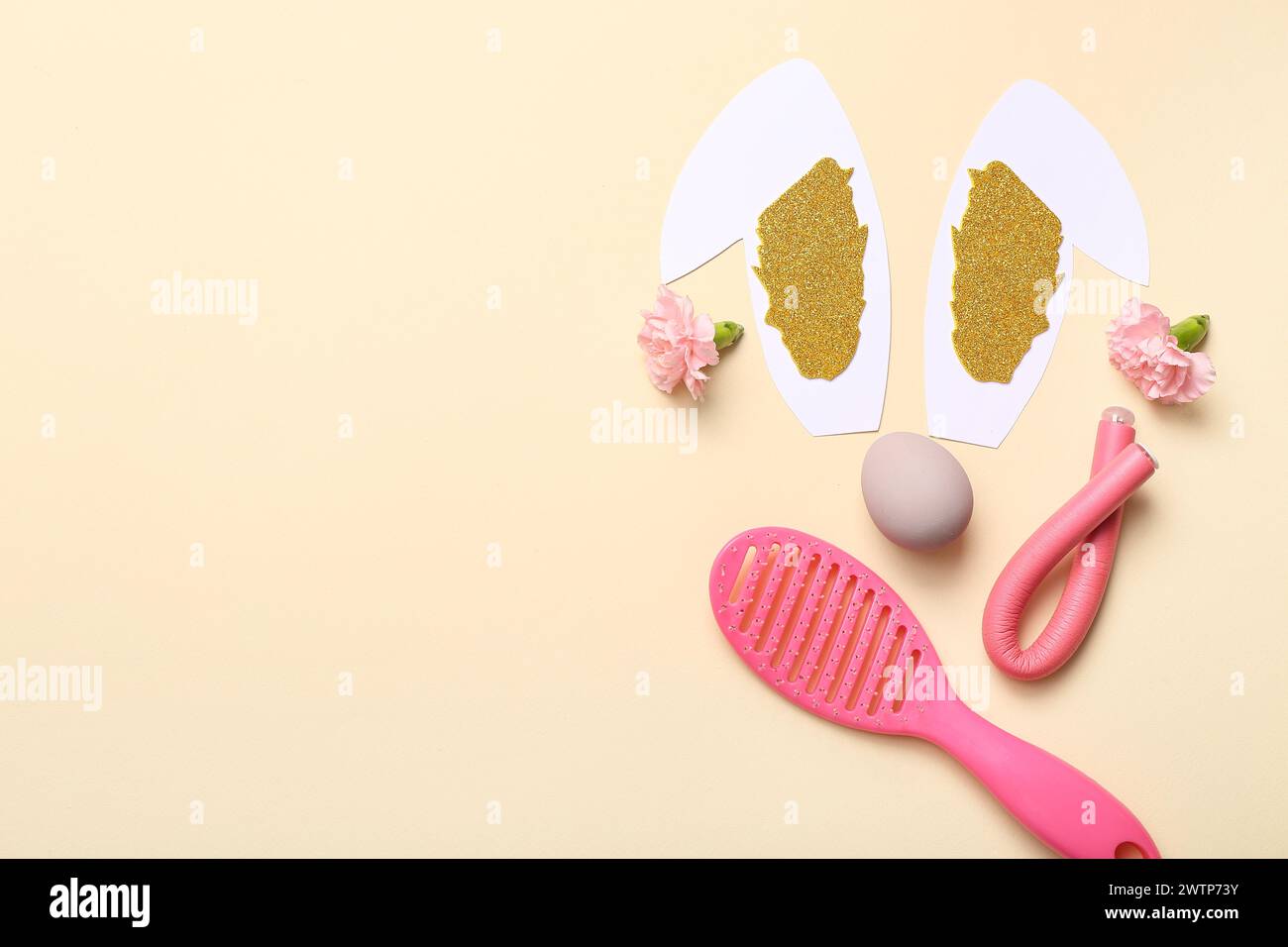 Accessori per parrucchieri con fiori, uovo di Pasqua e orecchie da coniglio su sfondo beige Foto Stock