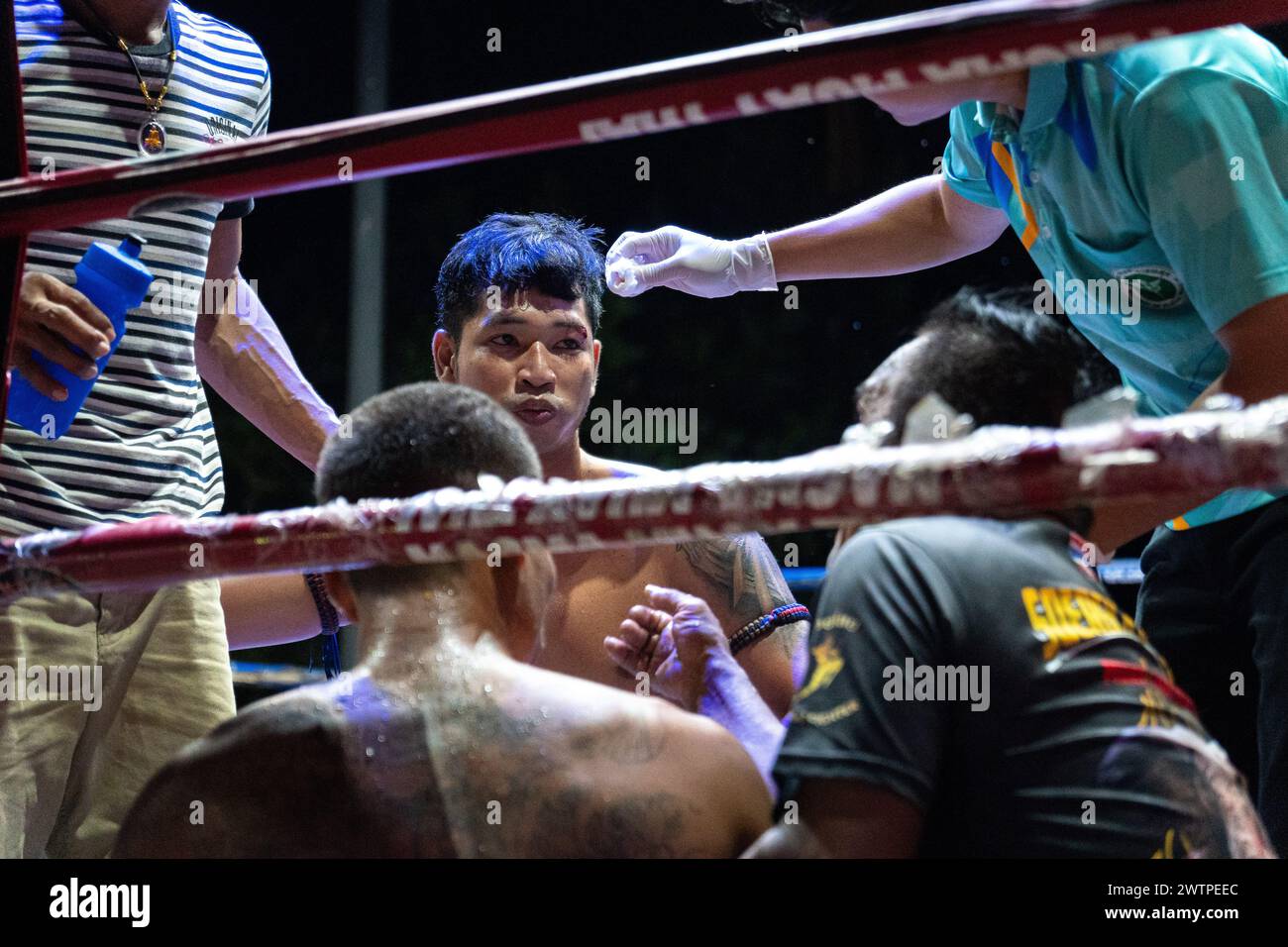 Il pugile vincitore Frame Payak (C) viene visto parlare con l'organizzatore mentre riceve un trattamento, durante i combattimenti Muay Thai, sull'isola di Koh Chang, Thailandia. Foto Stock