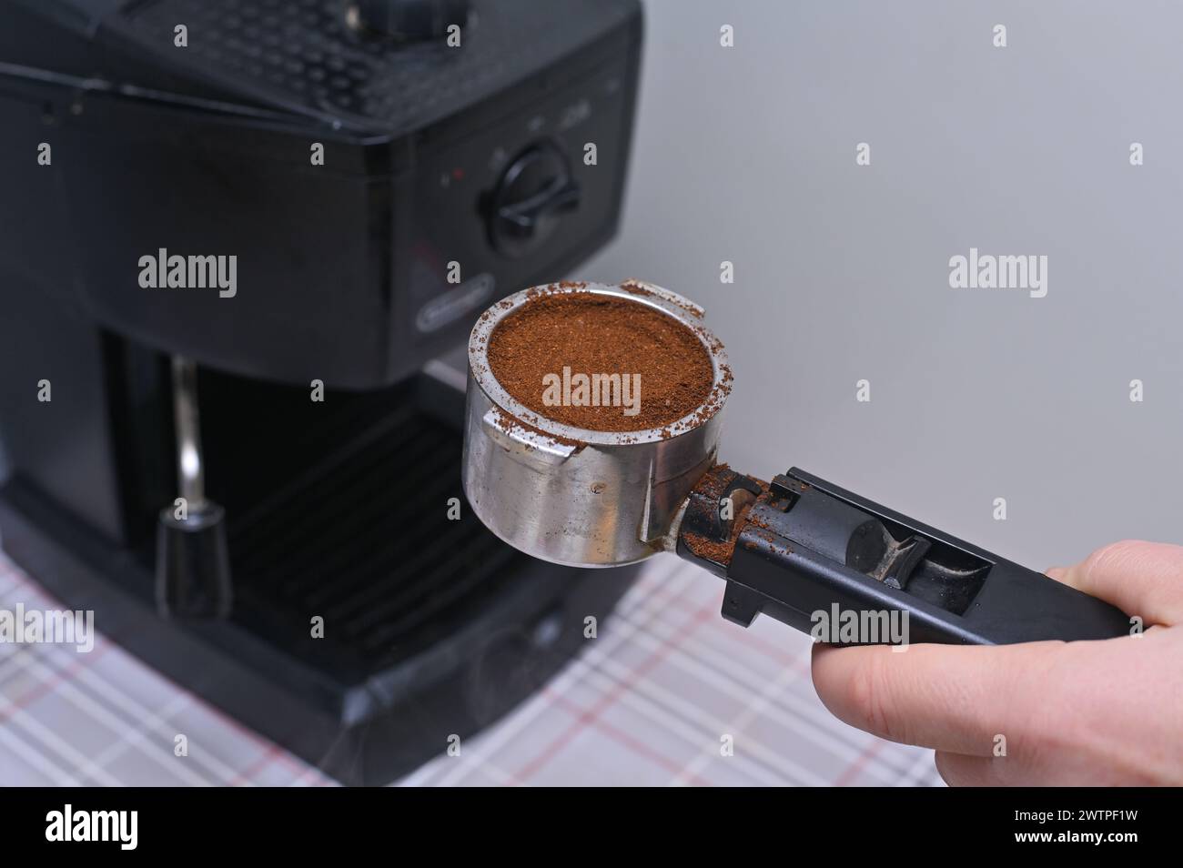 la mano di una donna mette il caffè macinato nella macchina del caffè Foto Stock
