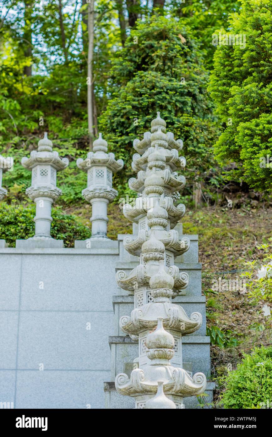Un'alta torre di lanterne ornamentali in pietra incastonata nel verde del fogliame, a Daejeon, Corea del Sud, Asia Foto Stock