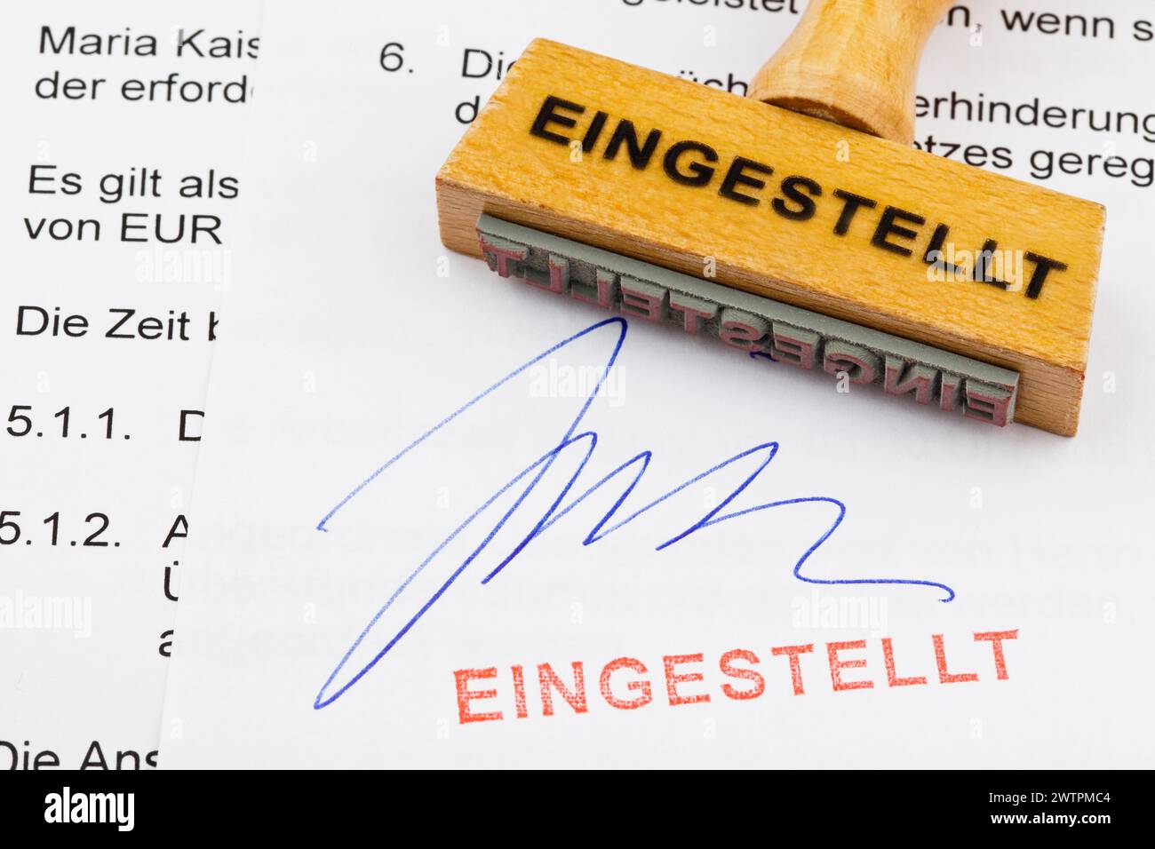 Un timbro di legno giace su un documento. Iscrizione tedesca: Eingestellt Foto Stock