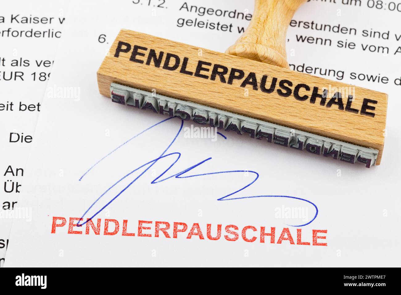 Un timbro di legno giace su un documento. Iscrizione tedesca: Pendlerpauschale Foto Stock