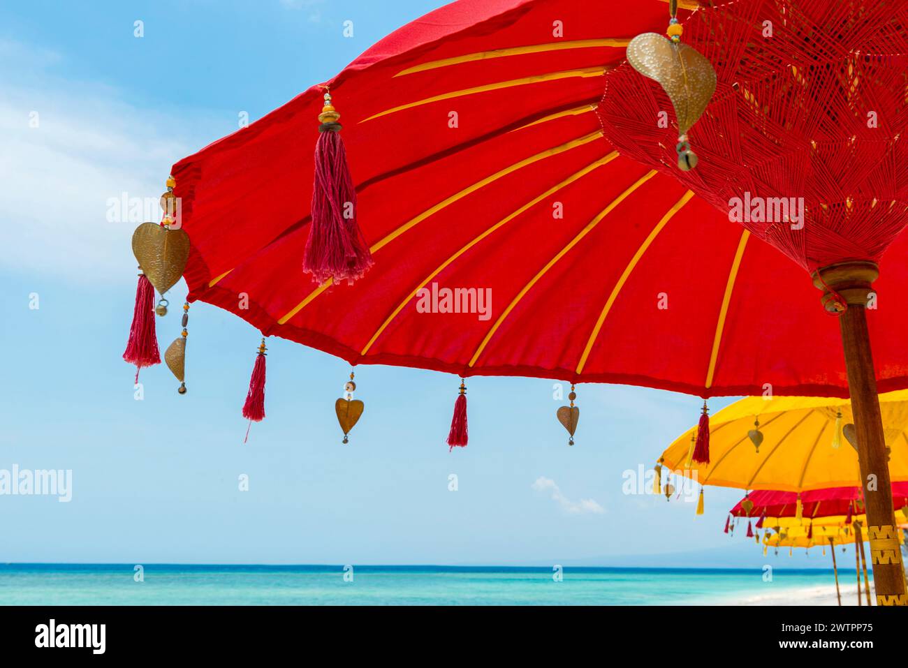 Tradizionale parasole balinese del tempio come ombrellone, induismo, simbolo, vacanza al mare, protezione, protezione solare, balinese, cultura, rosso, giallo, sole Foto Stock