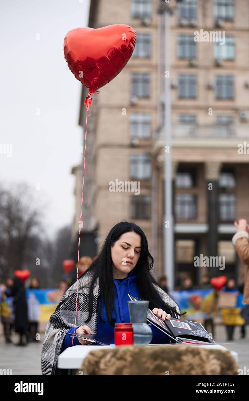 Donna triste che sfoglia le foto con suo marito, soldato dell'esercito ucraino, che rimane in prigionia russa dal 2022. Kiev - 16 marzo 2024 Foto Stock