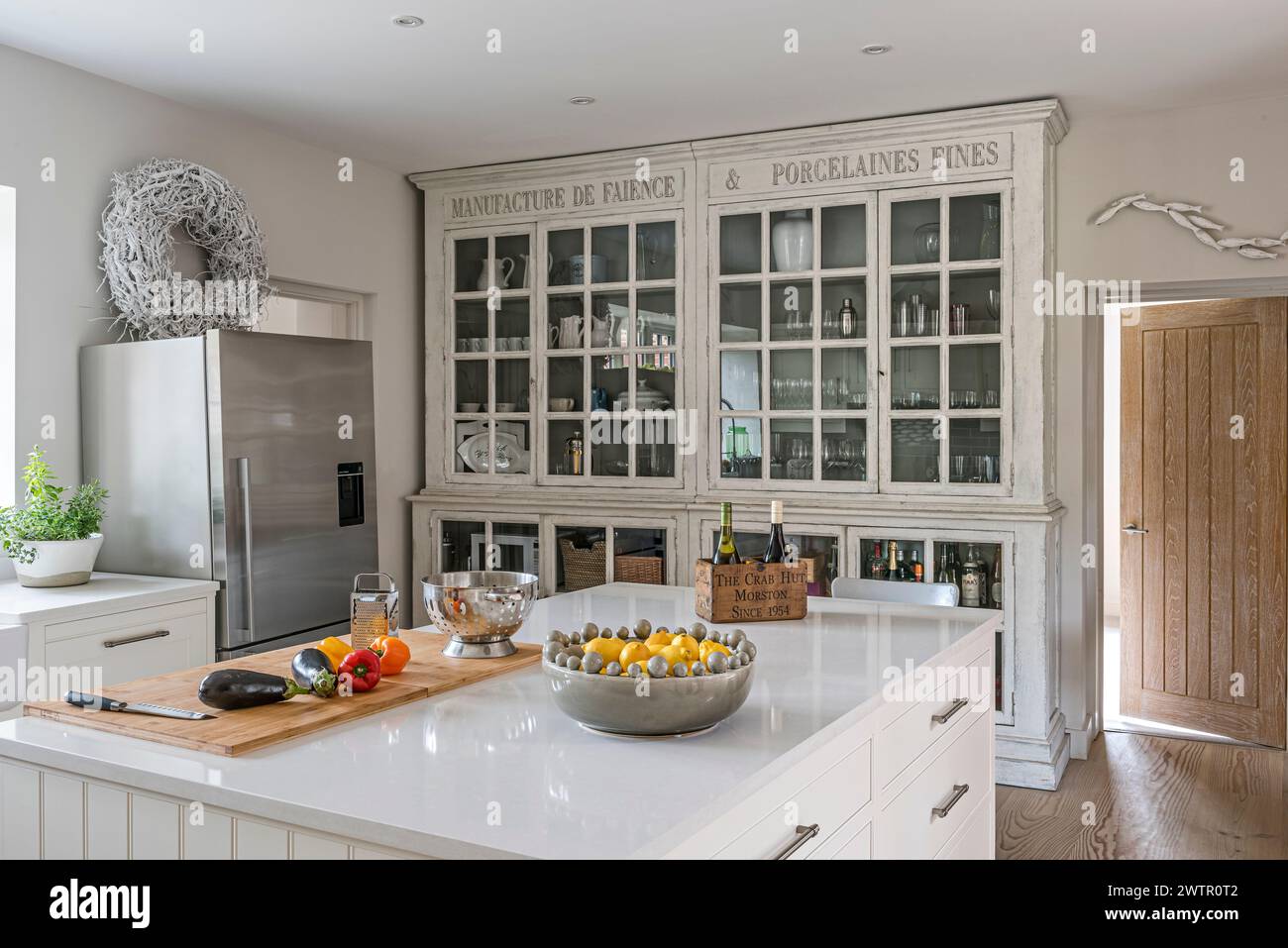 Comò da cucina con vista in vetro e frigorifero verticale nella casa britannica. Blakeney, Norfolk, Regno Unito Foto Stock