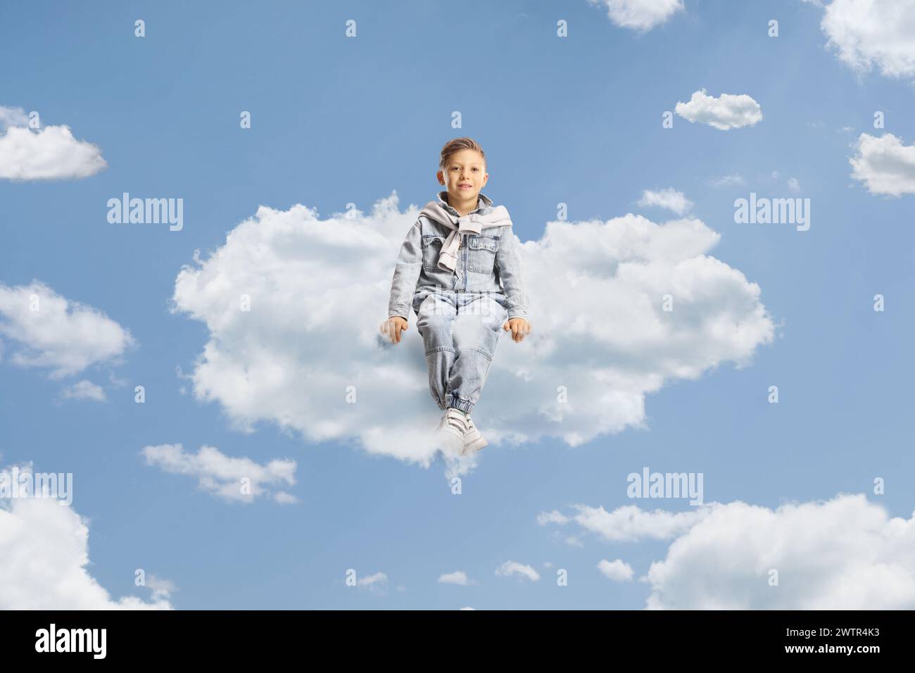 Bambino in jeans che galleggia su una nuvola nel cielo Foto Stock