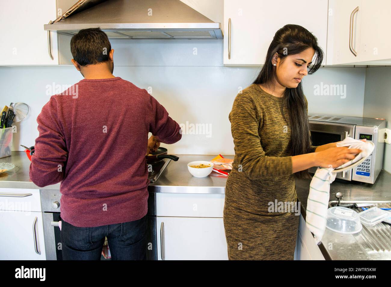 Studenti indiani che cucinano e fanno piatti Aquisgrana, Germania. Giovani coppie studentesse indiane che cucinano il pranzo e preparano i loro piatti all'interno della loro cucina dormatoria. MRYES Aachen Dormatory Kitchen Nortrhein-Westfalen Duitsland Copyright: XGuidoxKoppesx Foto Stock