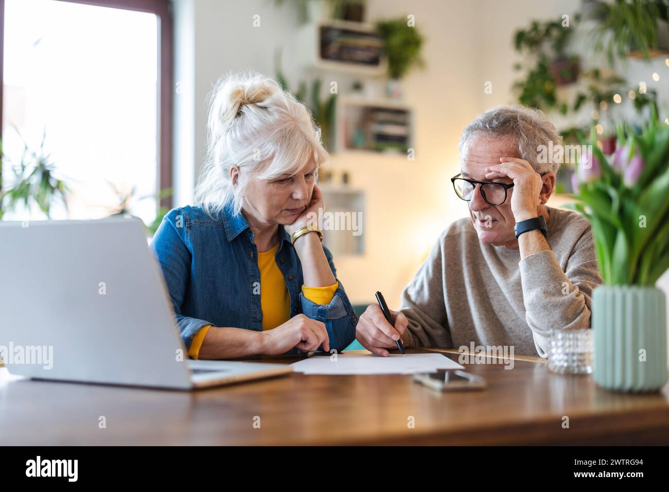 Una coppia anziana seduta al tavolo a discutere delle finanze domestiche Foto Stock