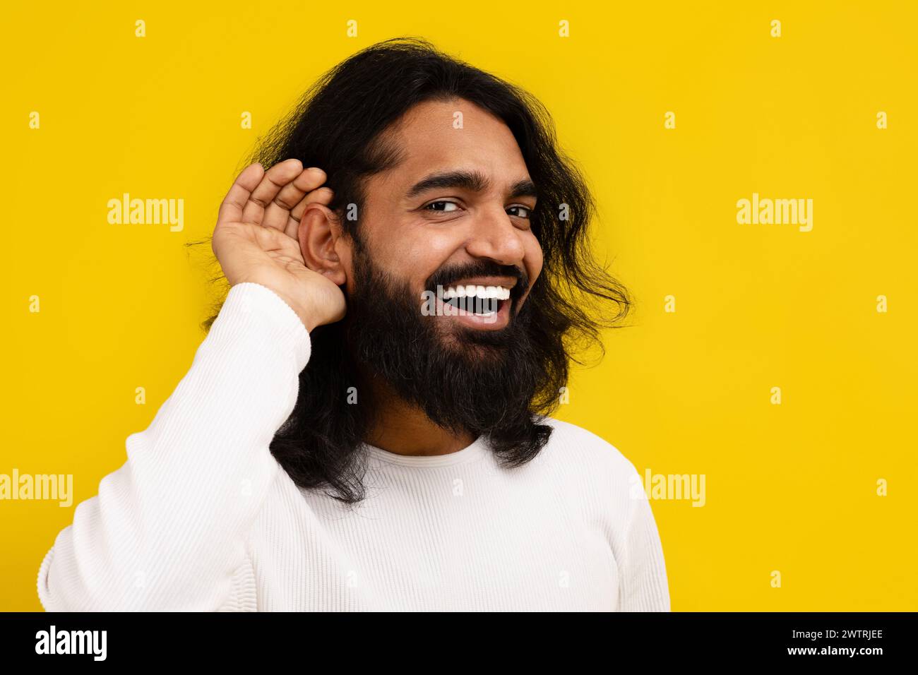 Curioso uomo indiano interessato che si tiene per mano vicino all'orecchio Foto Stock