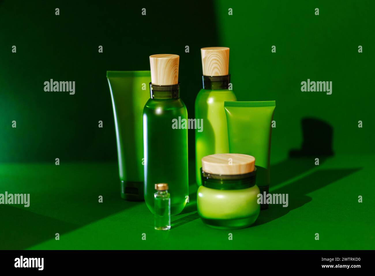 Un insieme di layout per i prodotti cosmetici. I mockup sono un biberon trasparente e traslucido con coperchio, tubi e vasetto di panna. Sfondo verde. N Foto Stock