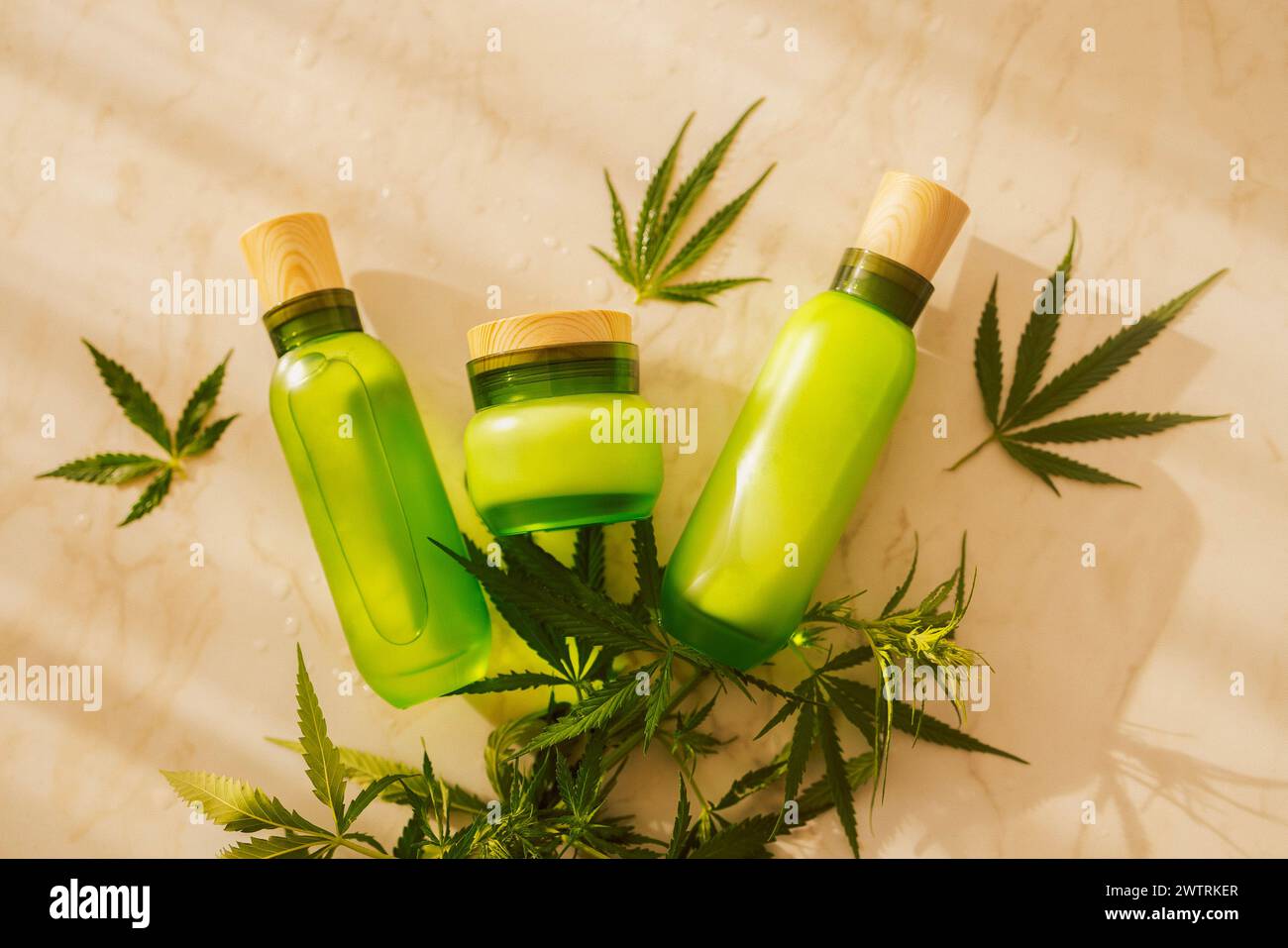 Una serie di layout per prodotti cosmetici con foglie di cannabis. I mockup sono un biberon trasparente e traslucido con coperchio e un vaso di panna con hel Foto Stock