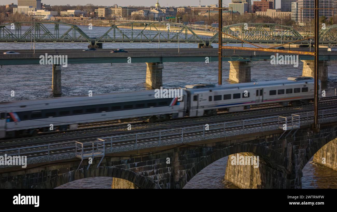 Un treno argentato che attraversa un ponte con altri treni nelle vicinanze Foto Stock