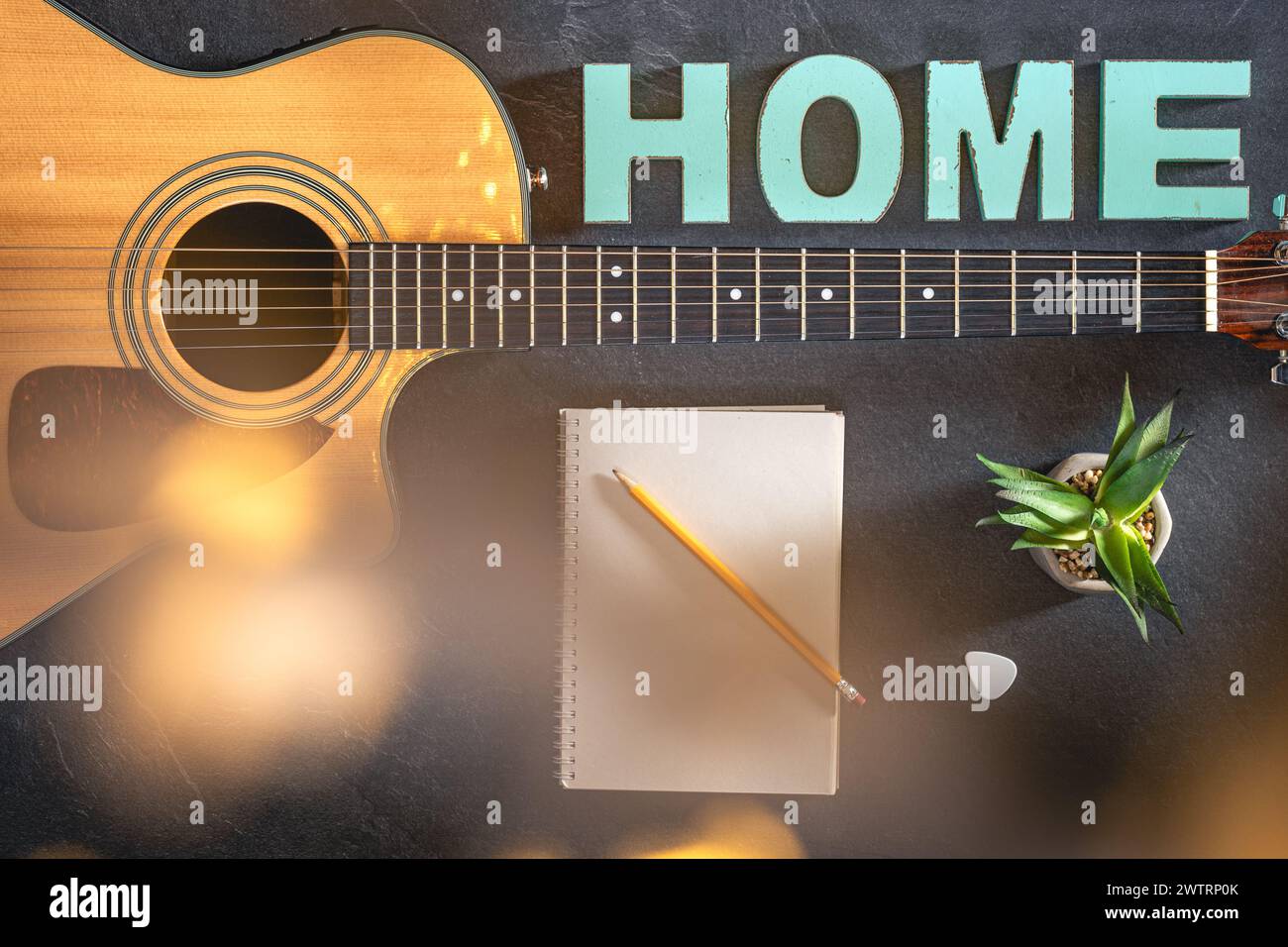 Chitarra acustica, blocco note e parola decorativa Home, vista dall'alto. Foto Stock