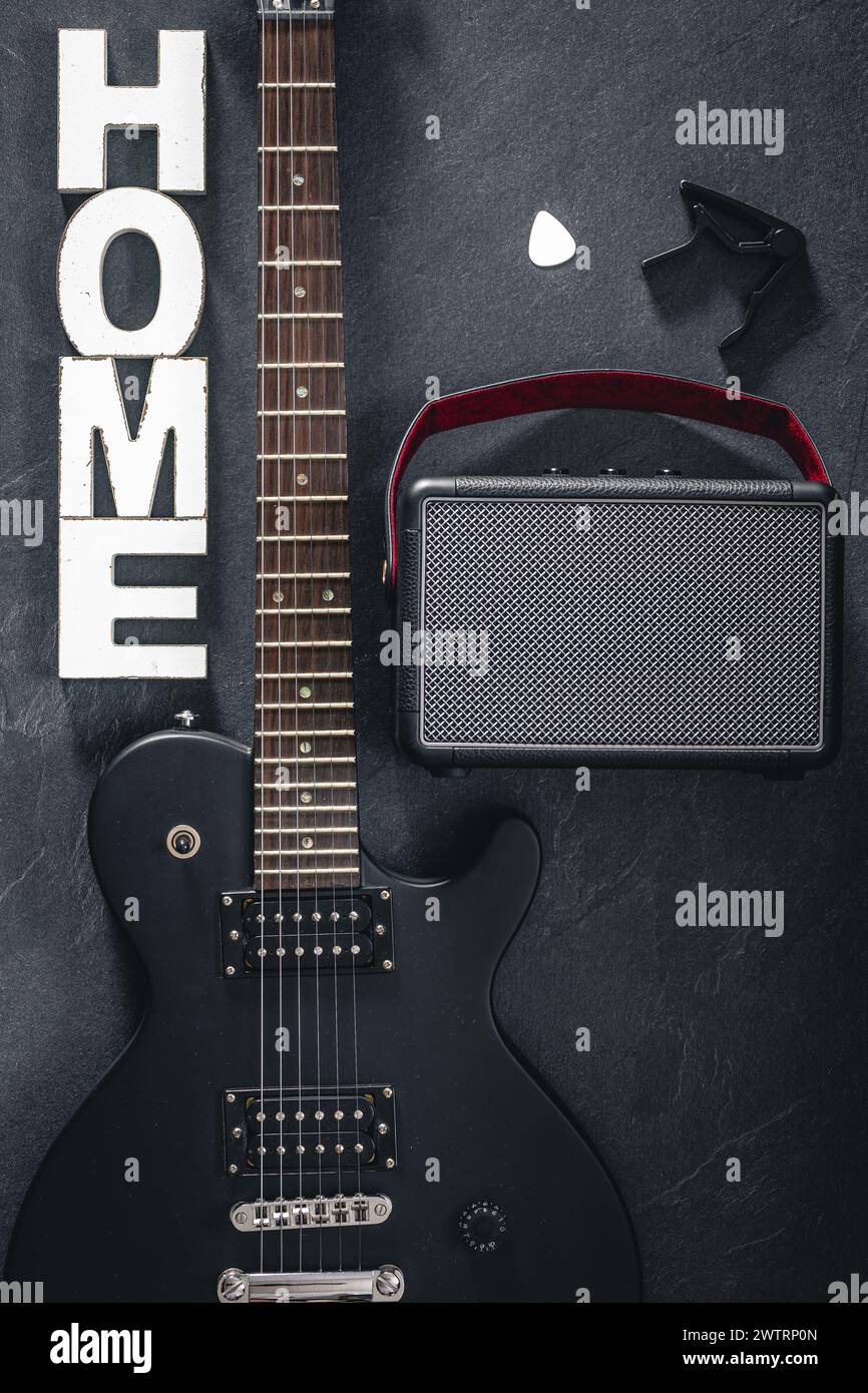 Chitarra elettrica e amplificatore su sfondo scuro con la parola decorativa Home. Foto Stock