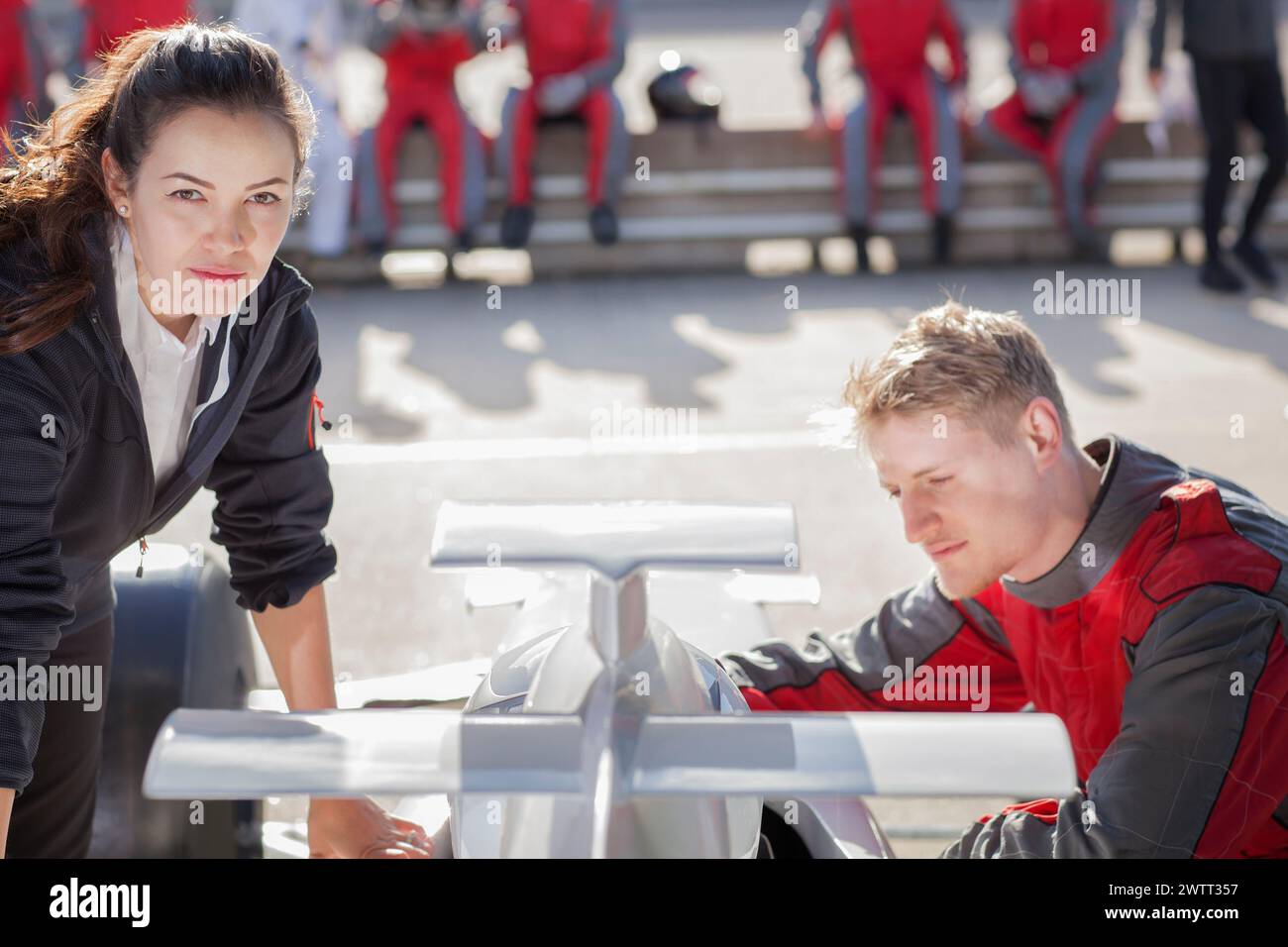 Pilota di auto da corsa e ingegnere che pianificano la strategia sul circuito Foto Stock
