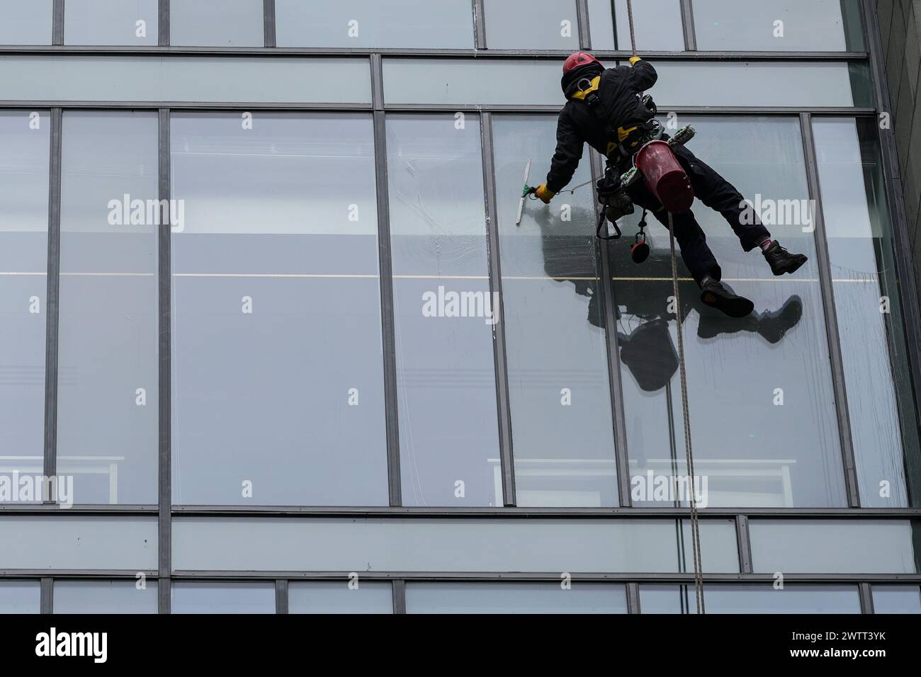 I lavavetri sospesi su funi puliscono le finestre esterne di un edificio di uffici a Glasgow, Scozia. Foto Stock