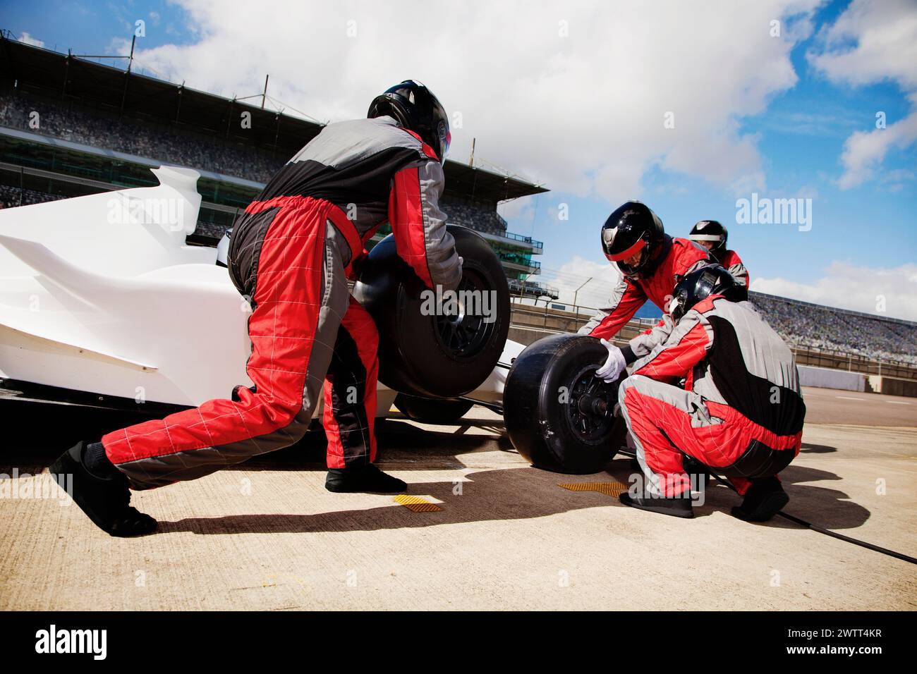 Il team dei box in azione sincronizzata durante il cambio degli pneumatici di un'auto da corsa ad alta velocità Foto Stock