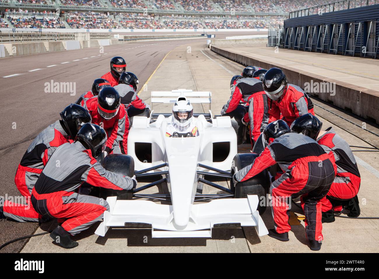 Pit crew in perfetta sintonia con la manutenzione di un'auto da corsa in pista. Foto Stock