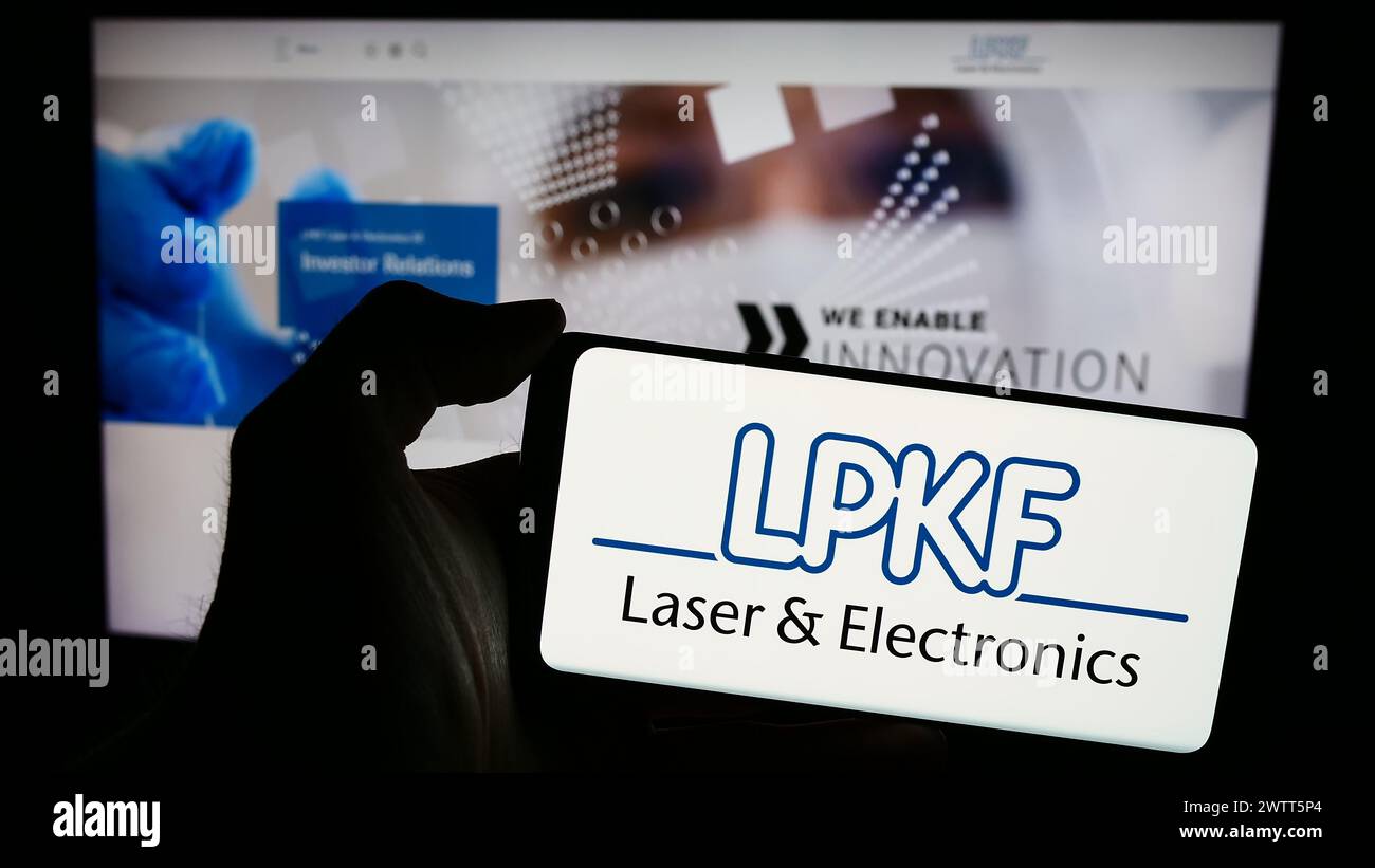 Persona che possiede uno smartphone con il logo dell'azienda tecnologica tedesca LPKF laser Electronics se davanti al sito Web. Mettere a fuoco il display del telefono. Foto Stock