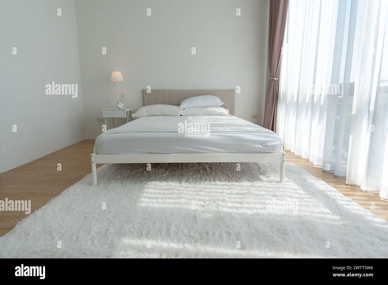 Camera da letto bianca con tende bianche e cuscini bianchi la mattina Foto Stock