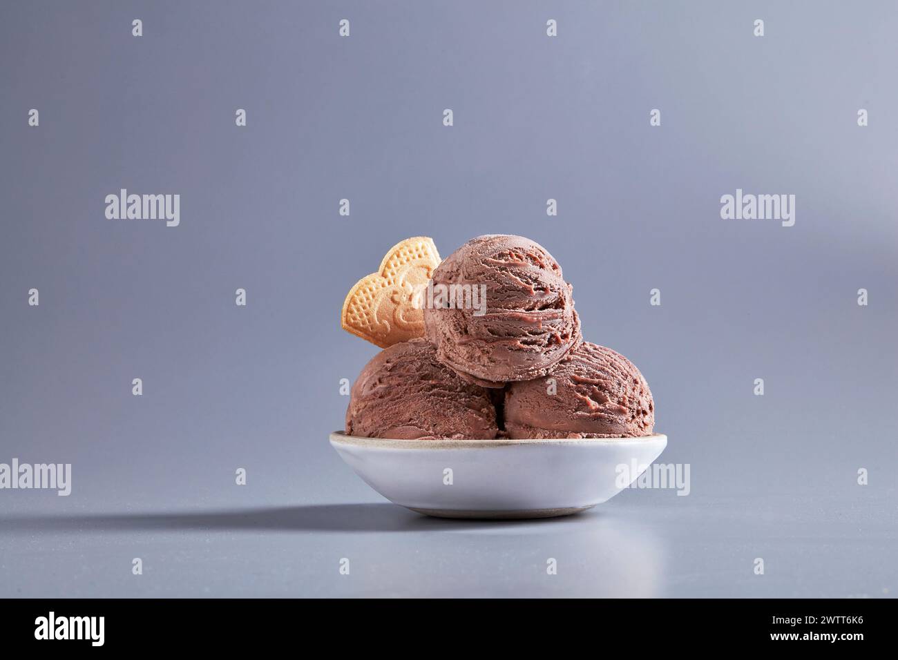 Una deliziosa tazza di gelato al cioccolato in un recipiente con cialde su sfondo grigio. Foto Stock