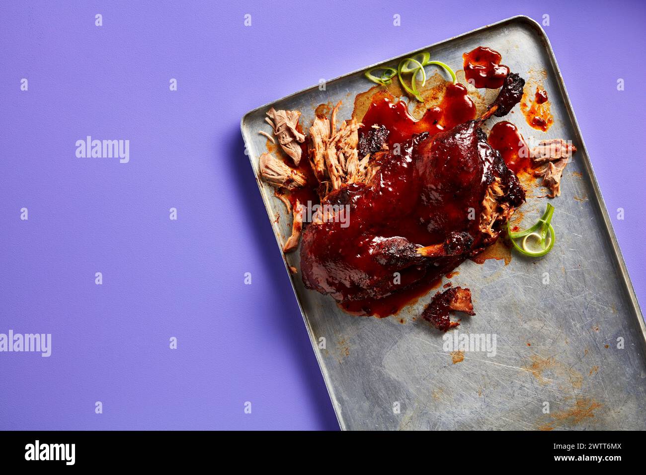 Carne di maiale tirata salata con salsa barbecue su un vassoio di metallo su sfondo viola Foto Stock