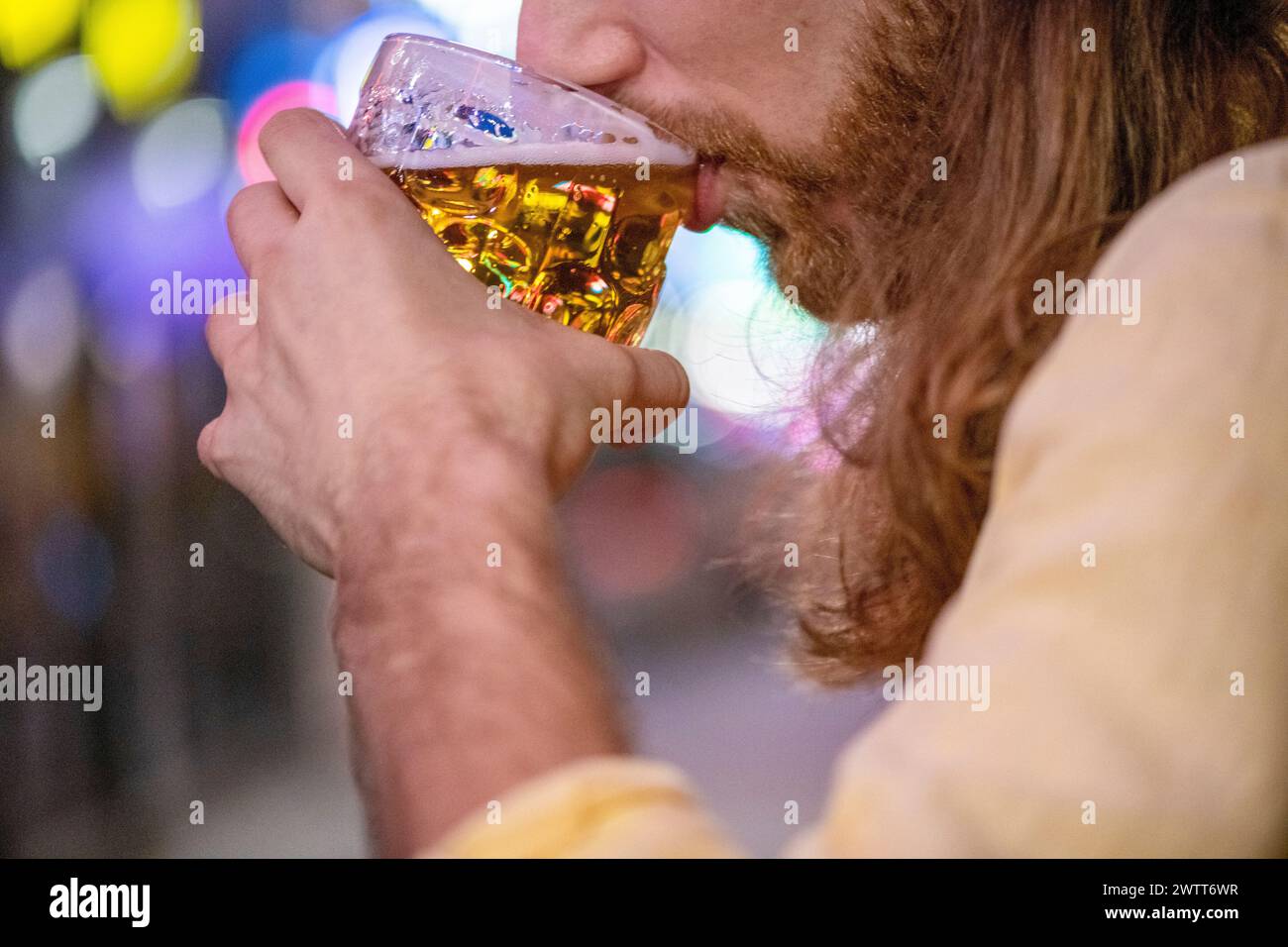 Uomo che assaggia una birra fredda di notte per le strade della città Foto Stock